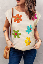 Tan crochet knit top with colorful floral appliqués and cap sleeves.