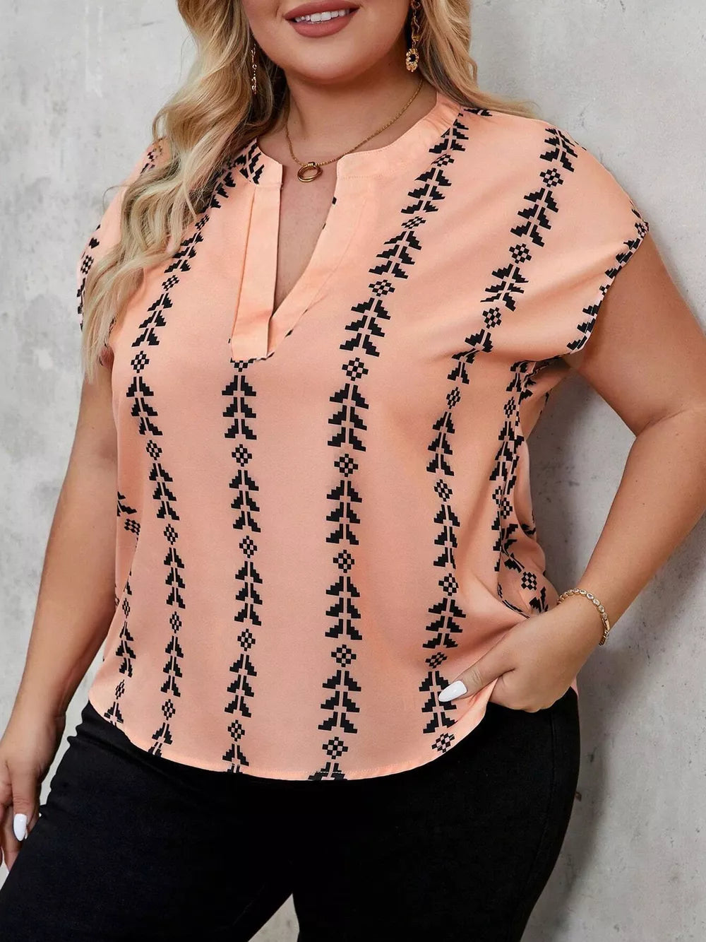 Plus-size peach v-neck blouse with black geometric stripes and short sleeves