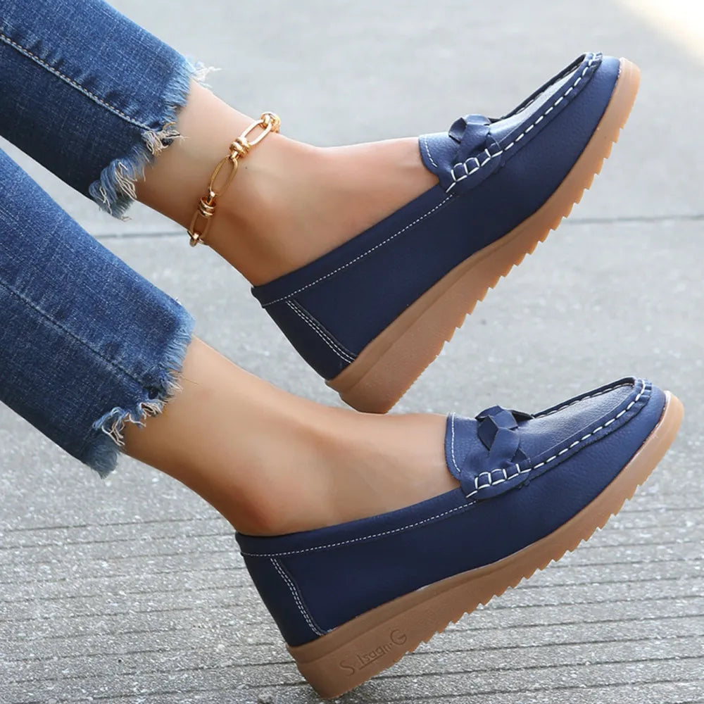 Dark blue leather loafers with braided detail and white stitching.