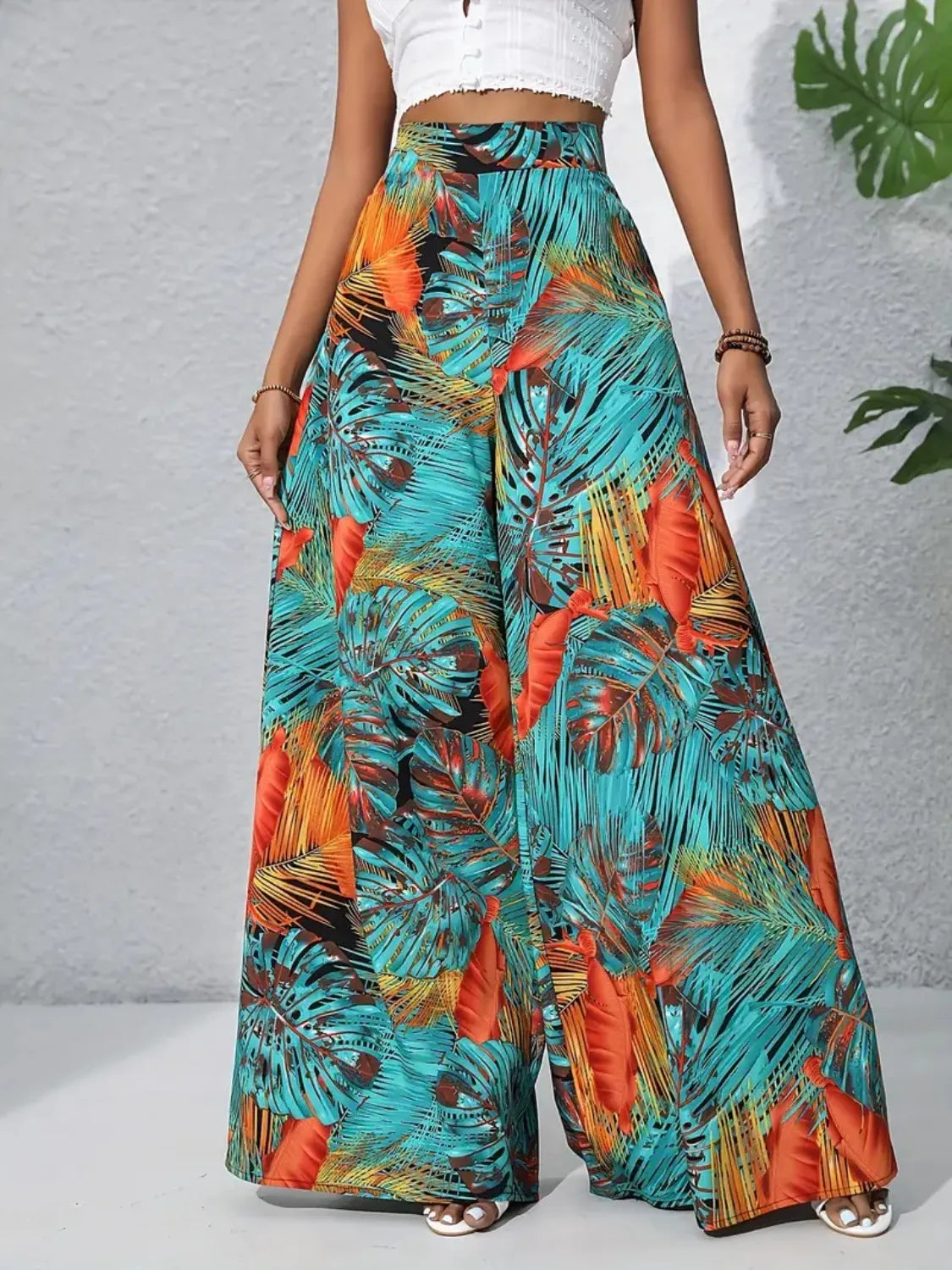 Palazzo trousers with tropical leaf print in teal and orange, made of 100% polyester.