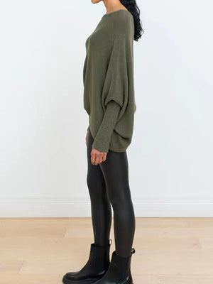 Army green knit sweater with off-shoulder neckline and textured cuffs, styled with black leggings.
