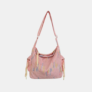 Pink slouchy shoulder bag with colorful embroidered abstract pattern and tassel detail.