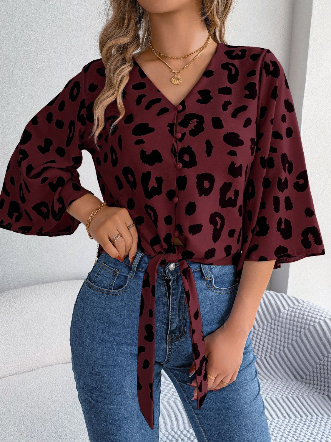 Burgundy leopard print tie-front blouse with button detail and bell sleeves.