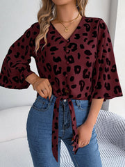 Burgundy leopard print tie-front blouse with button detail and bell sleeves.