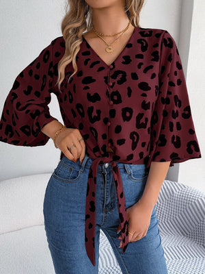 Burgundy leopard print tie-front blouse with button detail and bell sleeves.