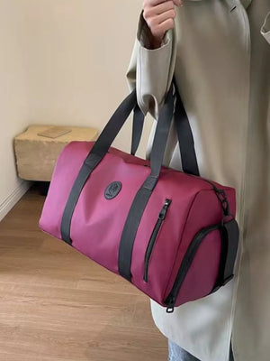 Wine red travel bag with adjustable straps and zippered pockets.