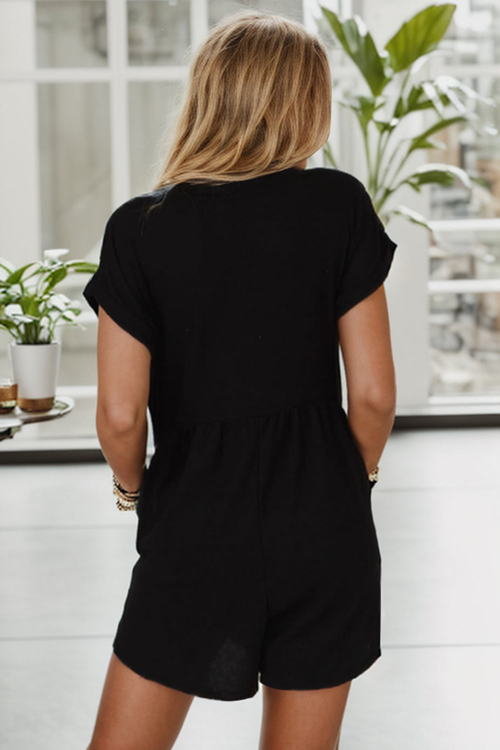 Black empire waist romper with short sleeves and gathered waist detail.