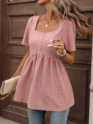 Pink eyelet babydoll top with square neck, puff sleeves, and decorative buttons.
