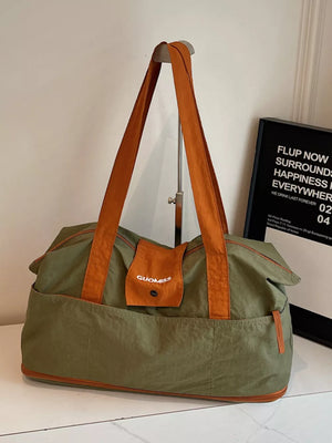 Green nylon travel bag with orange trim and handles, featuring exterior pockets and a small flap pocket with logo.