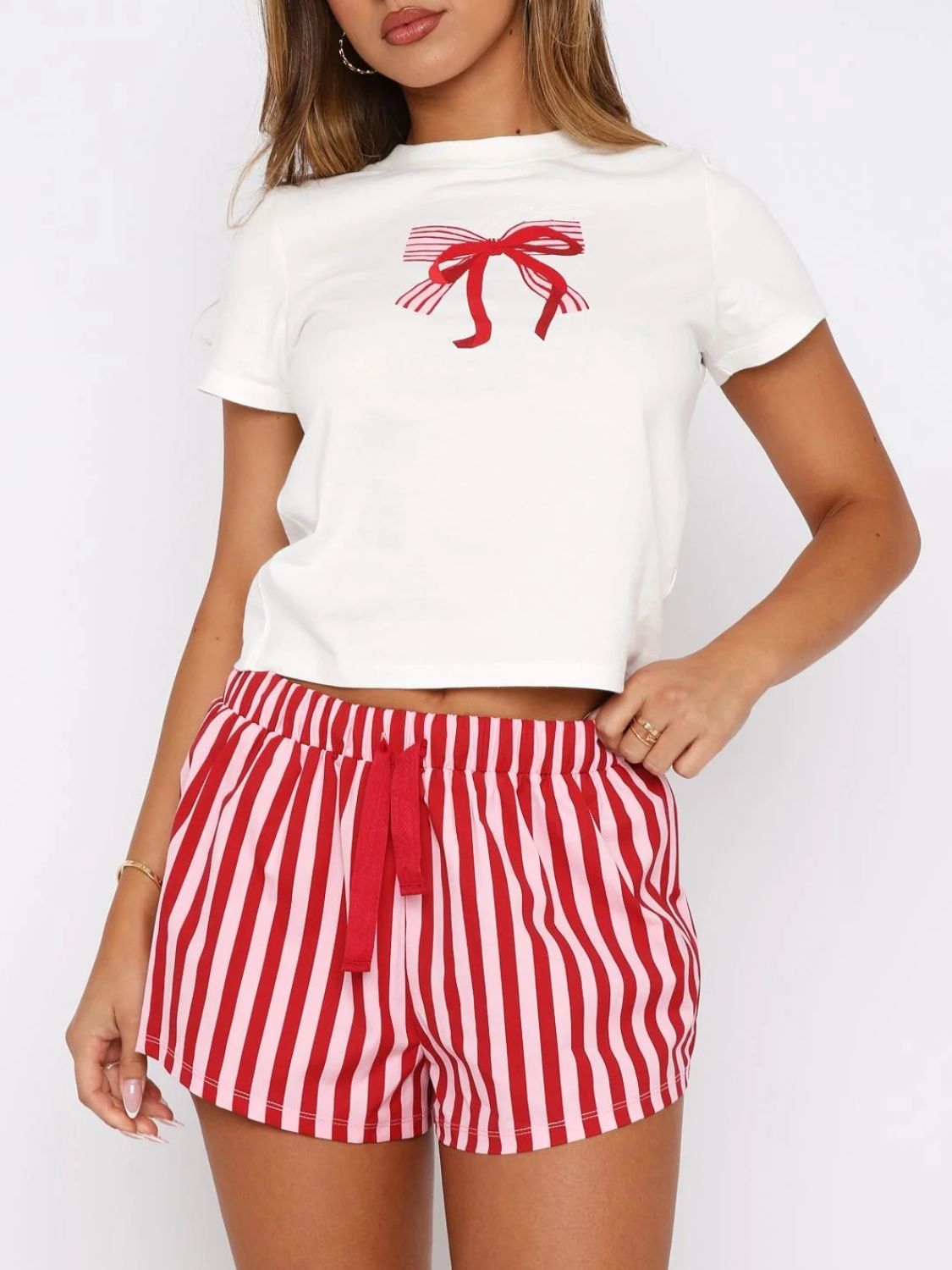 White tee with red bow graphic and red & pink striped lounge shorts with drawstring.