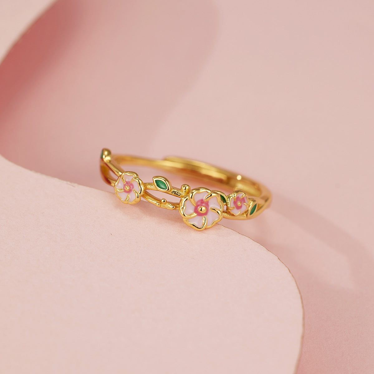 Gold adjustable ring with delicate pink flowers and green leaves.
