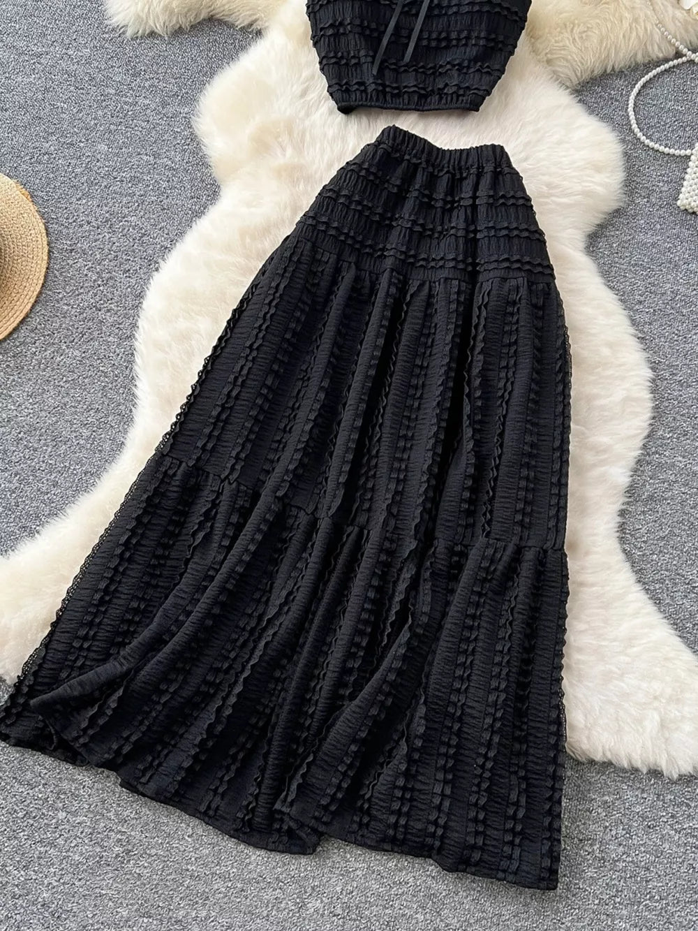 Black ruched polyester crop top and maxi skirt set with tiered ruffled detail.