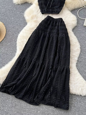 Black ruched polyester crop top and maxi skirt set with tiered ruffled detail.