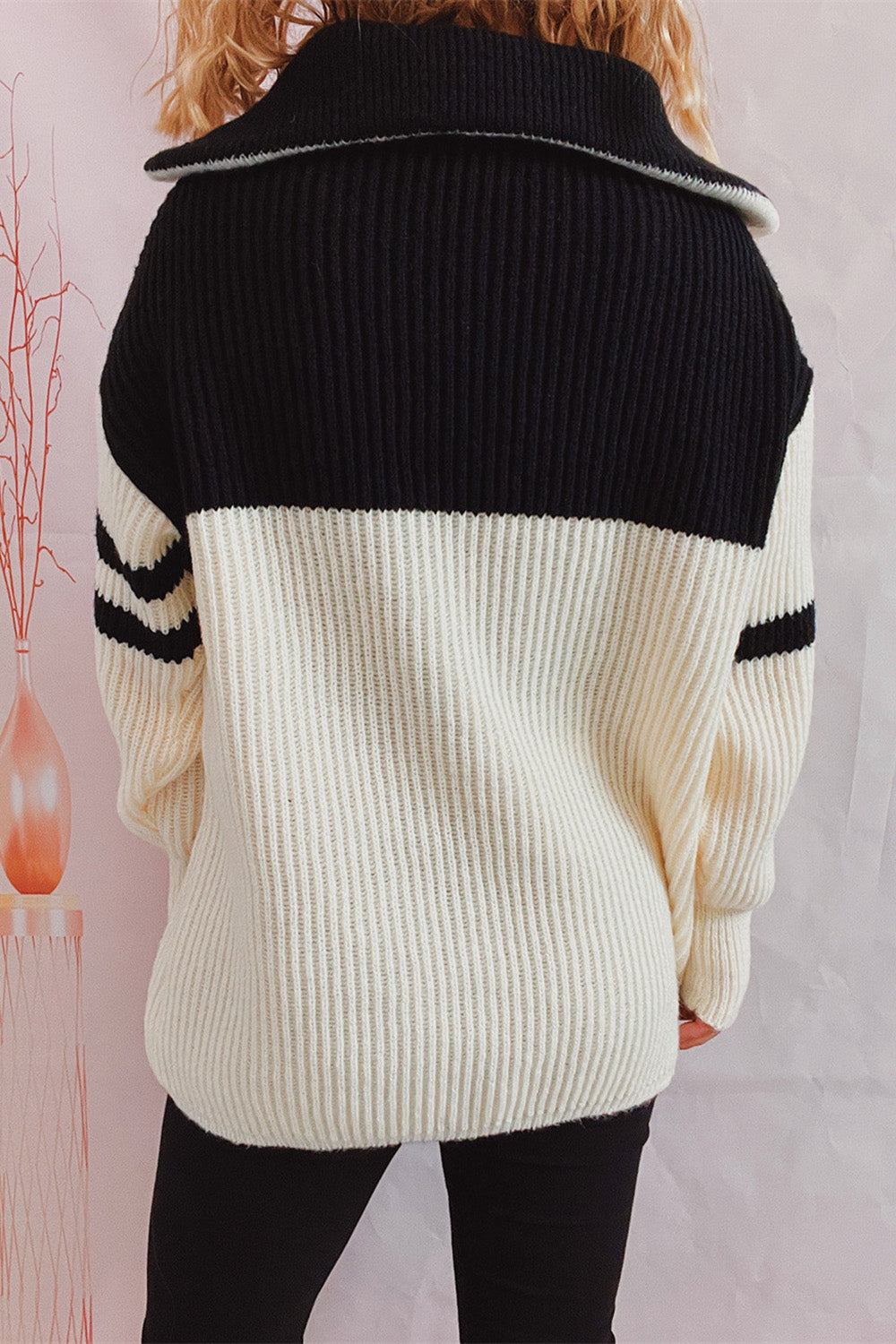 Ribbed knit quarter-zip sweater in black and white with striped sleeves.