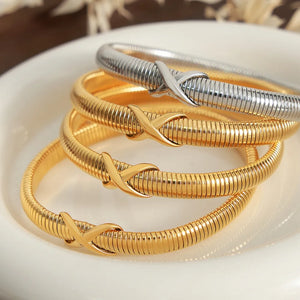 Ribbed X-detail bangle bracelets in gold and silver tones.