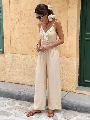 Cream lace-trimmed spaghetti strap romper with wide legs and cutout detail.