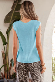 Light blue knit V-neck sweater vest with button details, styled with leopard print pants.