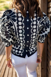 Black floral puff sleeve blouse with button-back detail and round neckline.
