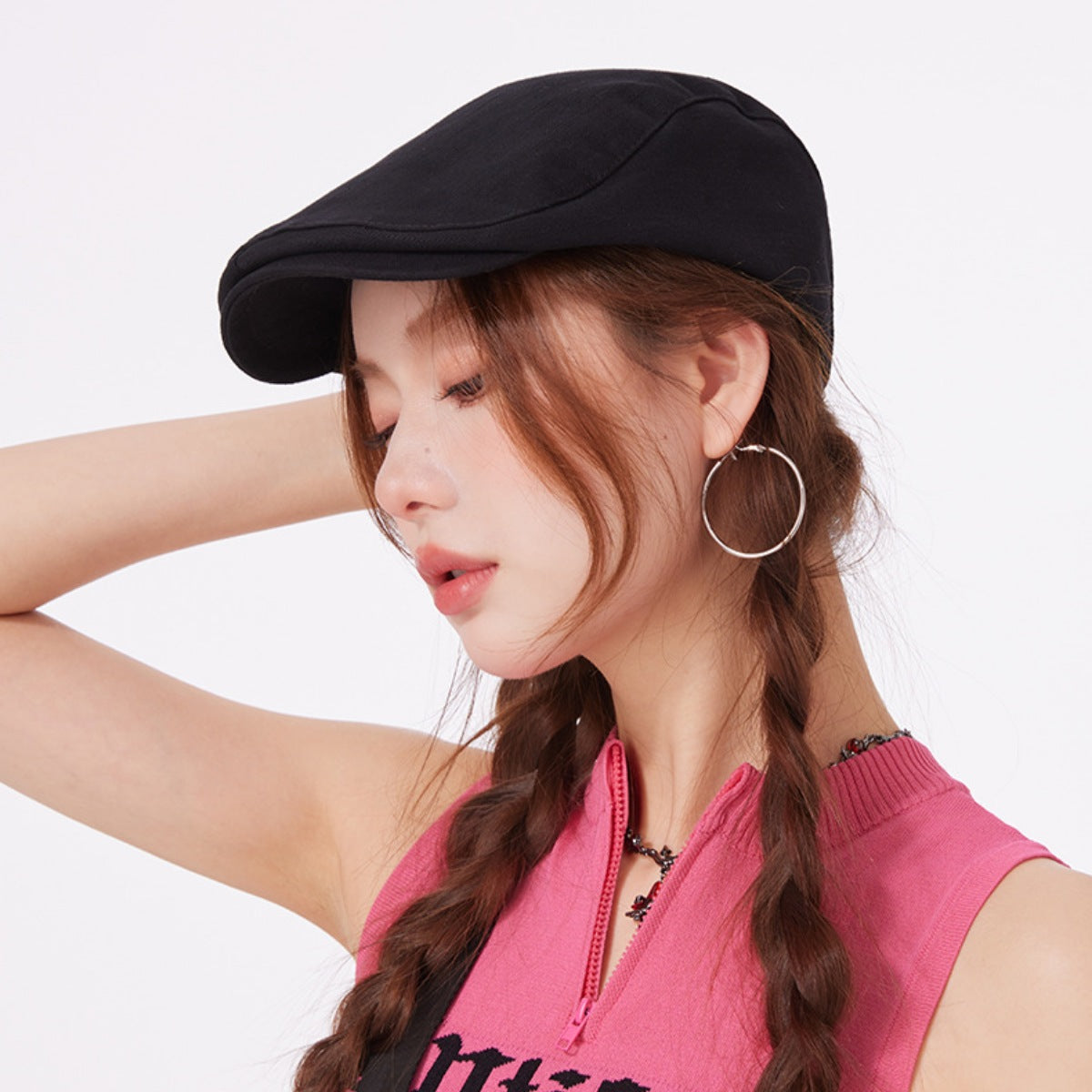 Black cotton newsboy cap with a flat brim, worn by a model with braided hair.
