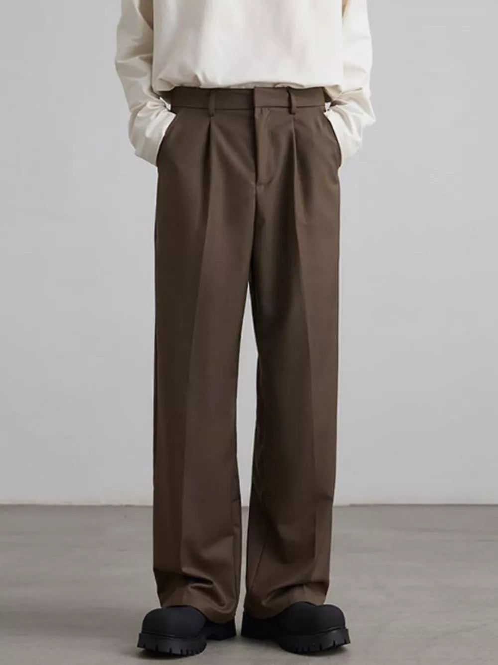 Brown pleated wide-leg trousers with a relaxed fit, styled casually.