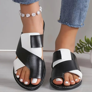 Two-tone black and white crossover toe-loop sandals with a flat sole.