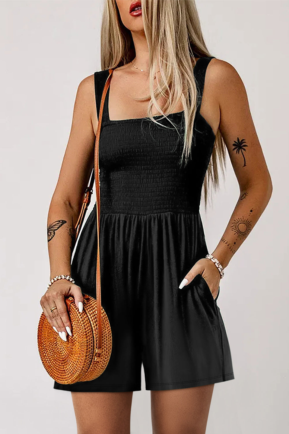 Black smocked bodice romper with square neckline and pockets, styled with a crossbody bag.