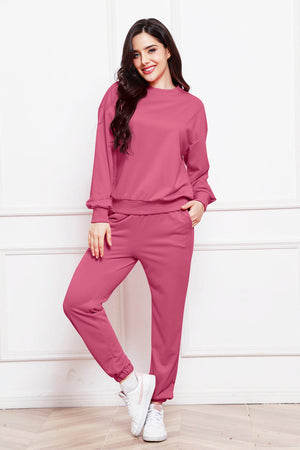 Relaxed fit loungewear set in hot pink, featuring a crewneck sweatshirt and matching joggers with cuffed ankles.