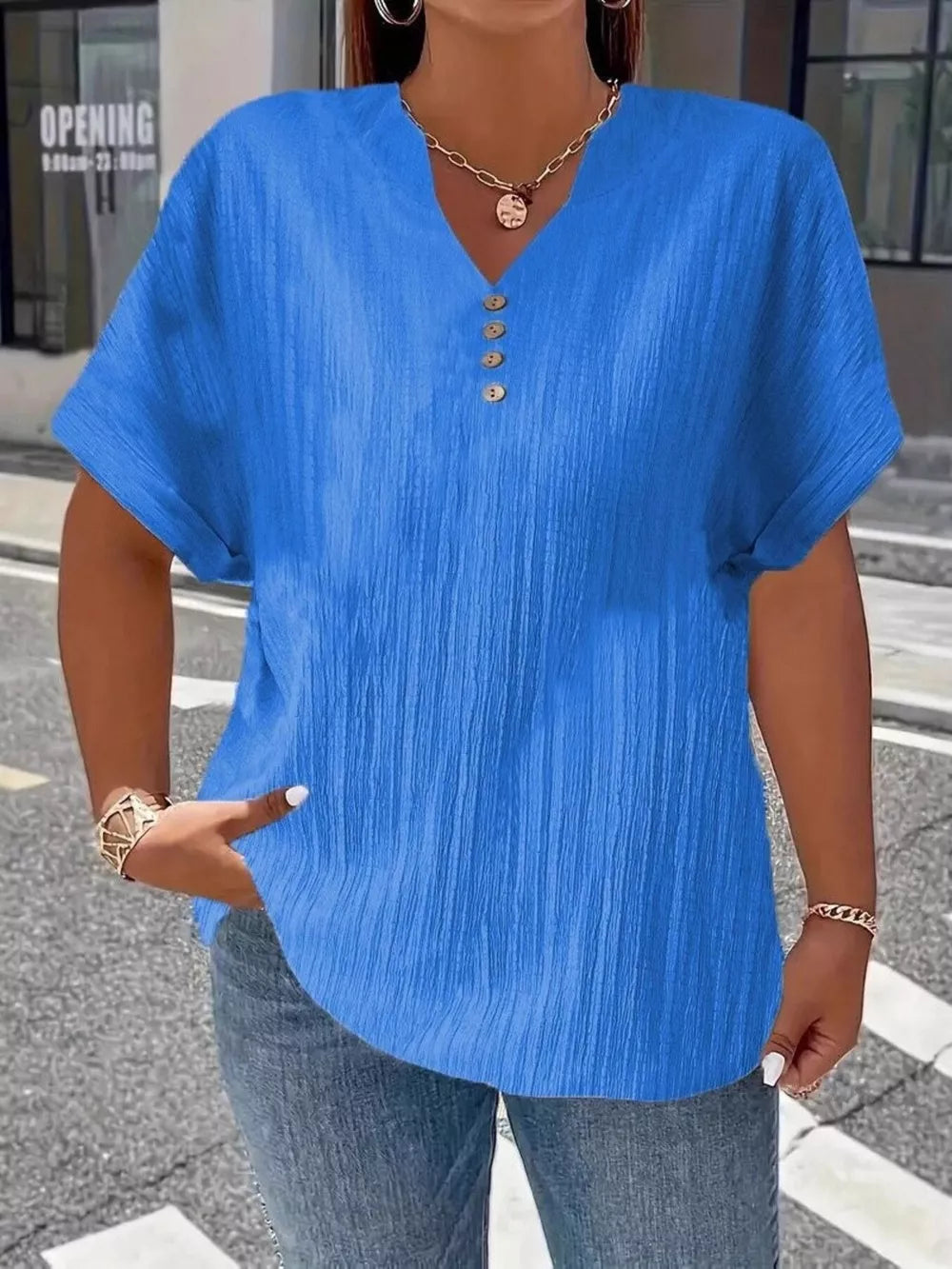 Blue textured V-neck t-shirt with decorative buttons and short sleeves.