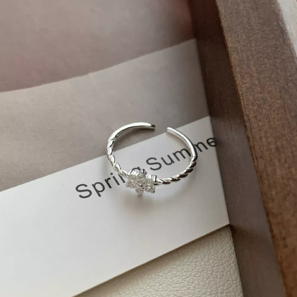 Sterling silver ring with twisted band and zircon flower detail.