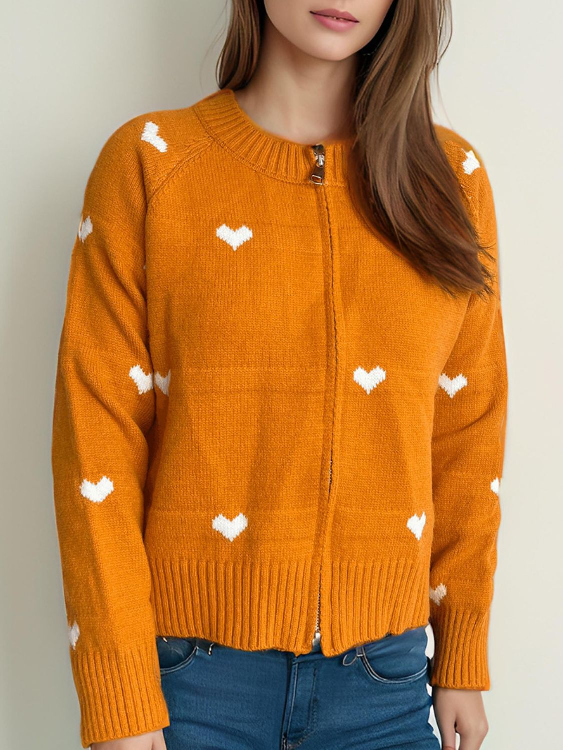 Orange zip-through knit cardigan with white heart pattern and ribbed cuffs.
