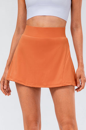 Performance pleated skort in caramel with a hidden pocket detail and wide waistband.