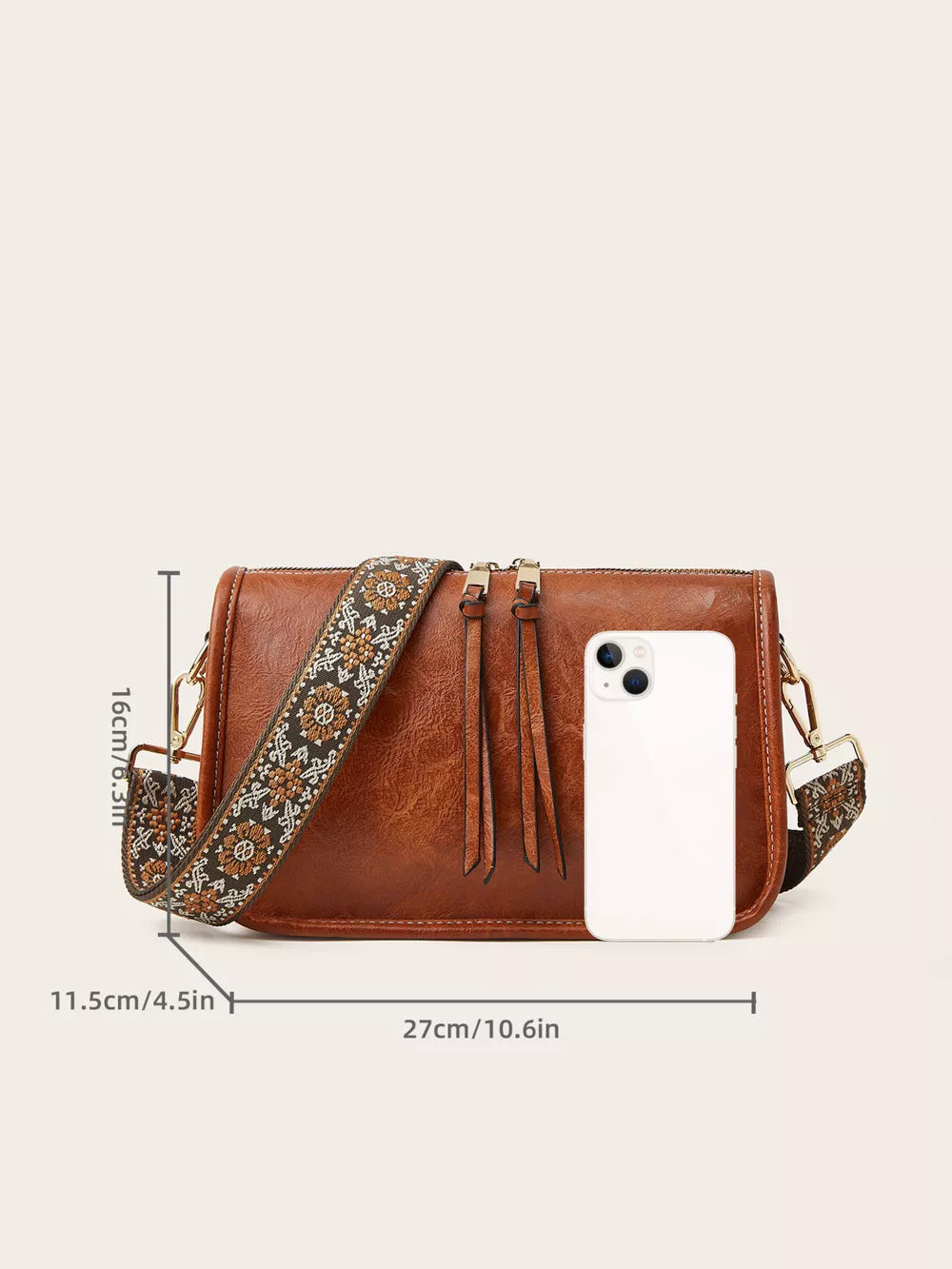 Tan leather crossbody bag with bohemian patterned strap and fringe details.