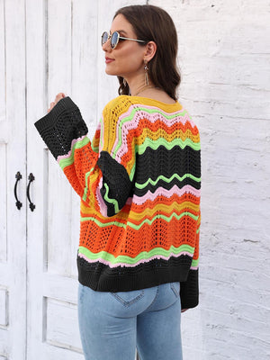 Crochet sweater with rainbow chevron stripes in orange, yellow, pink, green, and black, featuring bell sleeves.