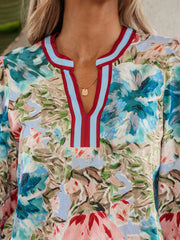 Women's cotton V-neck blouse with a colorful floral print and striped trim.