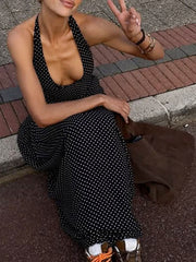 Black polka dot halter neck maxi dress with a low neckline and backless detail.