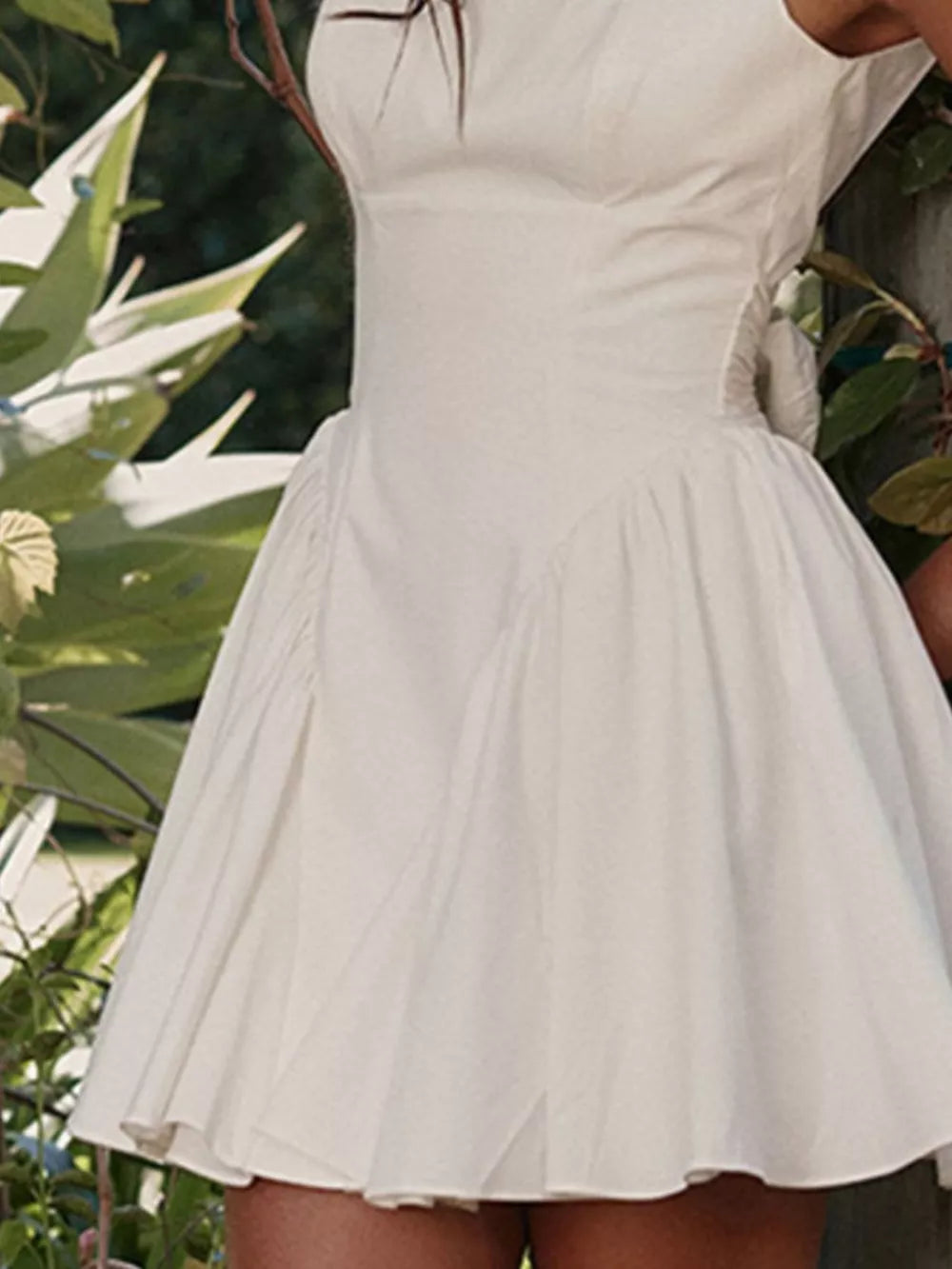 White backless mini dress with square neckline and bow detail.