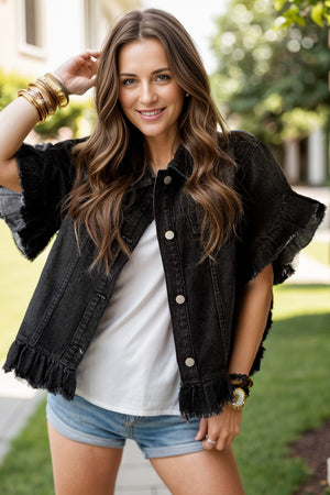 Black denim trucker jacket with ruffled hem and distressed sleeves.
