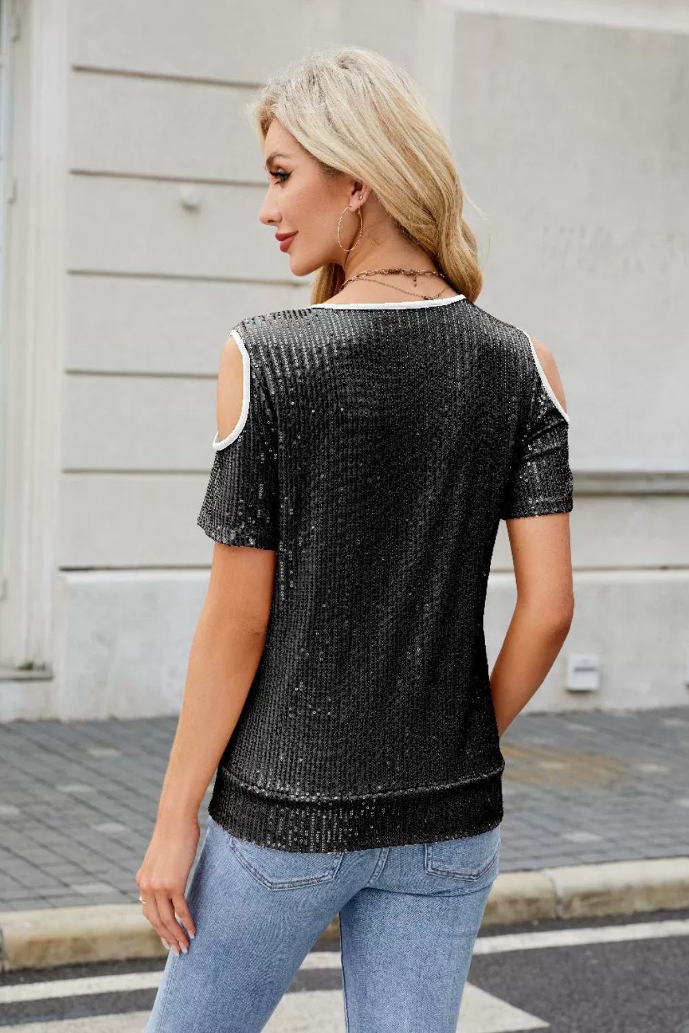 Black sequin cold shoulder blouse with white trim and short sleeves.