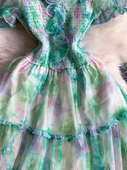 Floral tiered midi dress in light green with smocked bodice and ruffled details.