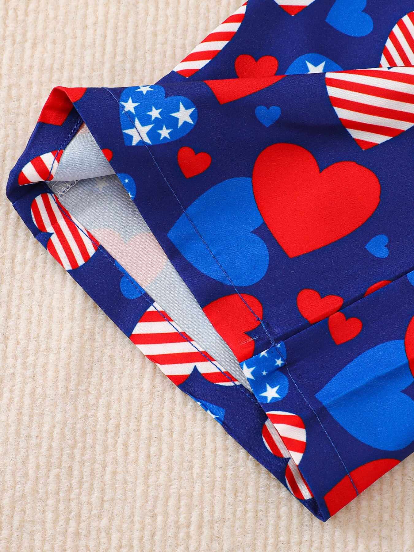 Patriotic baby outfit with heart and stars print on blue cotton fabric.