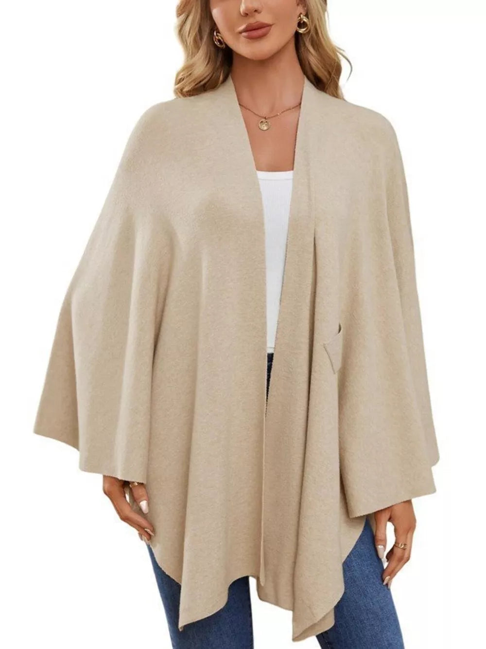 Beige knit cape top with draped elegance and tie front detail.