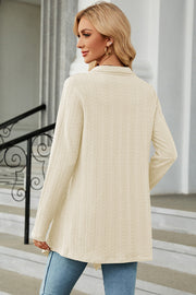 Cream textured knit cardigan with long sleeves and asymmetrical hem.