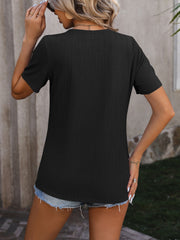 Black textured tee with short sleeves and a split hem, styled with denim shorts.