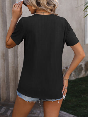 Black textured tee with short sleeves and a split hem, styled with denim shorts.
