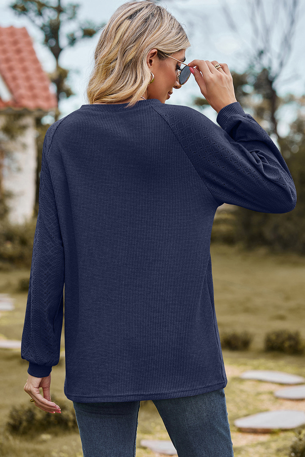 Dark blue waffle knit eyelet raglan sleeve top with textured sleeves.