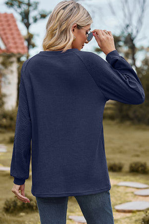 Dark blue waffle knit eyelet raglan sleeve top with textured sleeves.