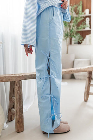 Light blue palazzo trousers with side tie details and pockets.
