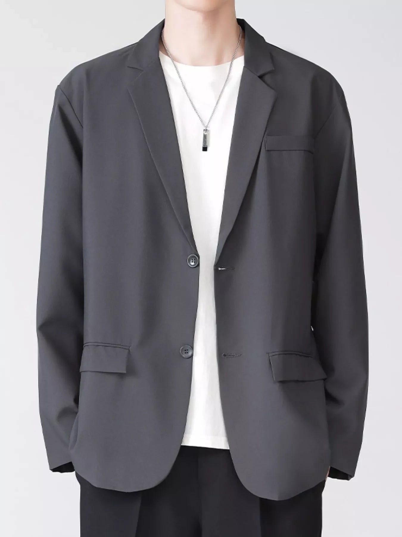 Men's grey lapel collar button up blazer with two buttons and flap pockets.