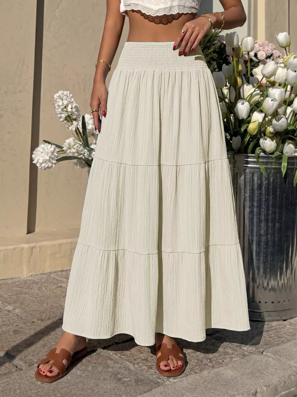 Smocked tiered maxi skirt in apricot with flowing fabric and textured detail.