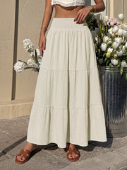 Smocked tiered maxi skirt in apricot with flowing fabric and textured detail.